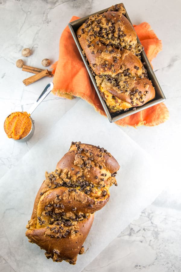 overhead view showing two loaves of pumpkin chocolate chip babka bread showing the twisted loaves with chocolate chip streusel on top.