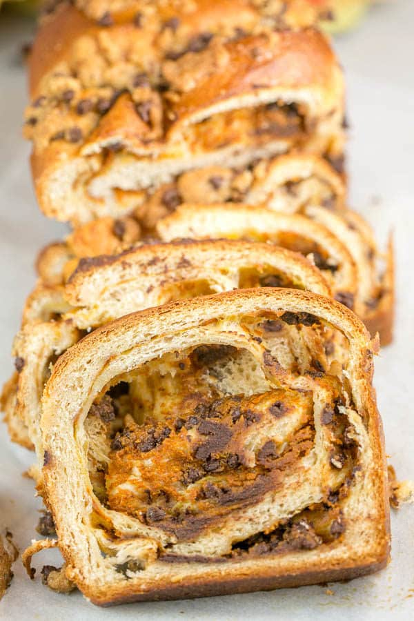 a loaf of pumpkin chocolate chip babka sliced and stacked showing the pumpkin and chocolate swirls in the bread