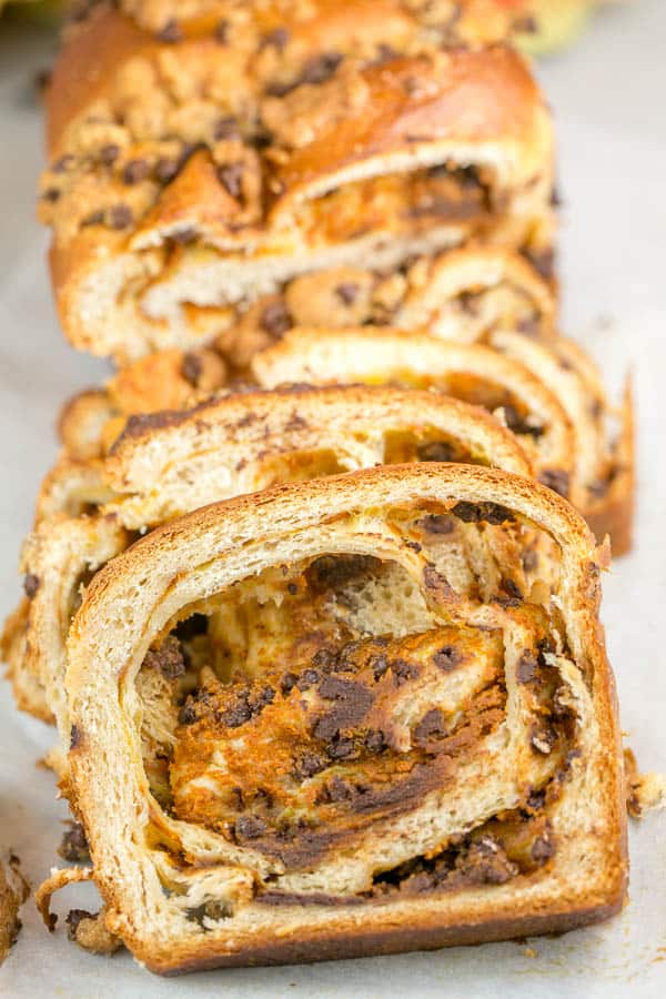 a loaf of pumpkin chocolate chip babka sliced and stacked showing the pumpkin and chocolate swirls in the bread.