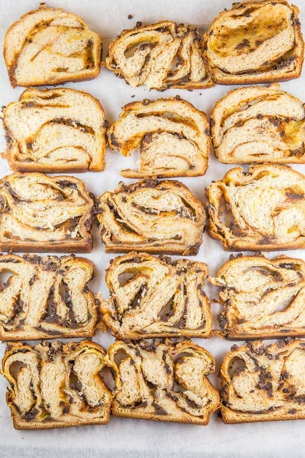 overhead view of sixteen slices of pumpkin chocolate chip babka arranged on a piece of parchment paper