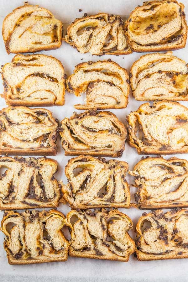 overhead view of sixteen slices of pumpkin chocolate chip babka arranged on a piece of parchment paper.