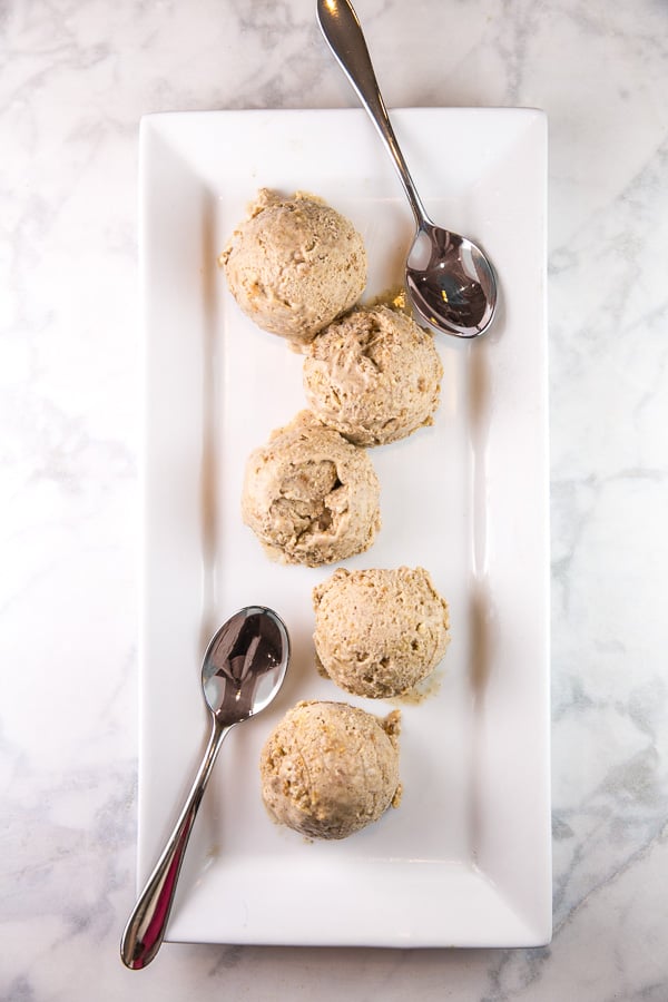 five scoops of oatmeal cookie ice cream on a white rectangular serving dish with two spoons on either end