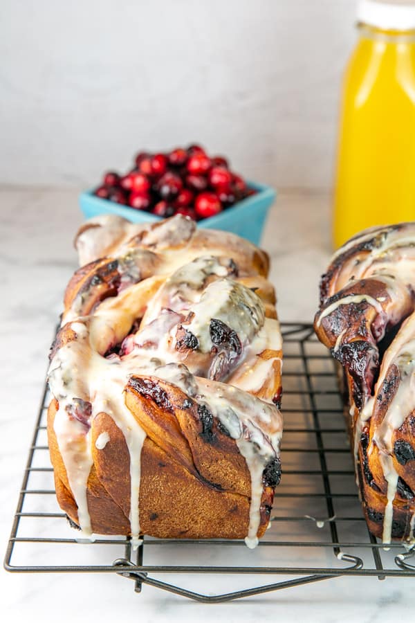 two loaves of cranberry orange babka on a cooling rack.