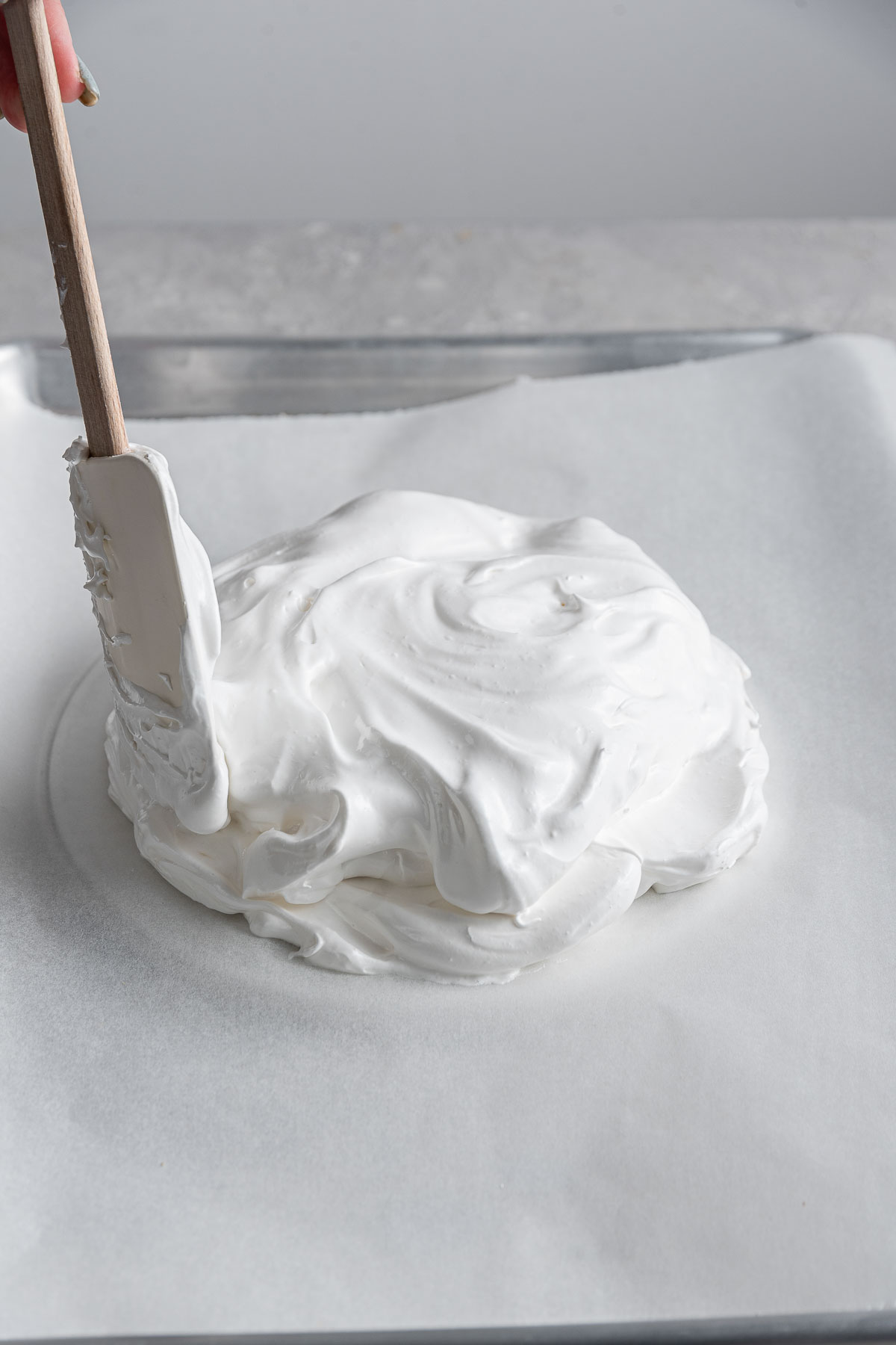 spatula spreading whipped egg whites into a circle