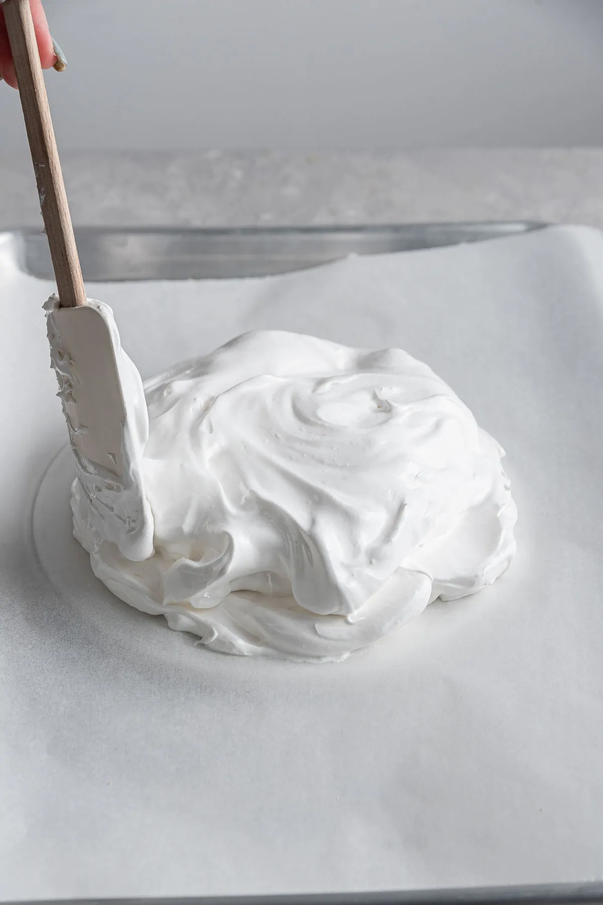 spatula spreading whipped egg whites into a circle