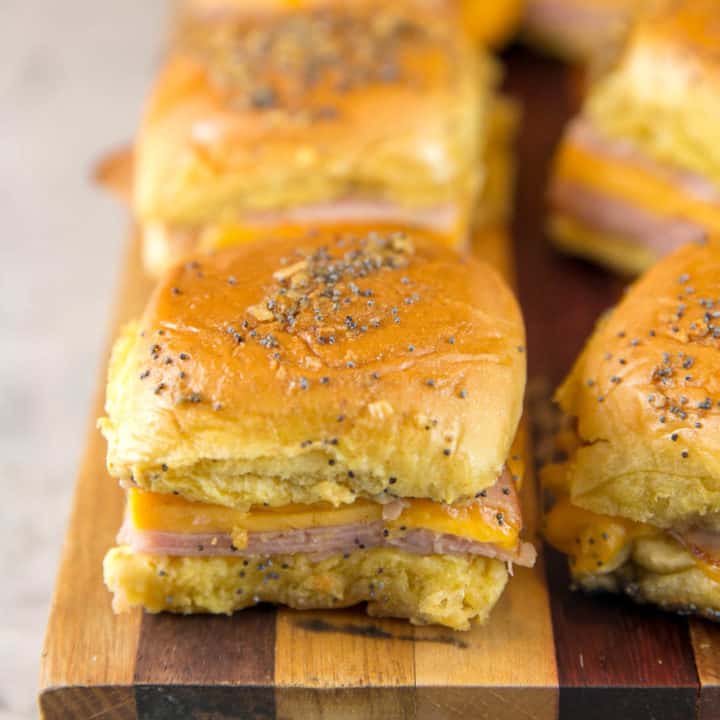 ham and cheese sliders on a wooden cutting board.