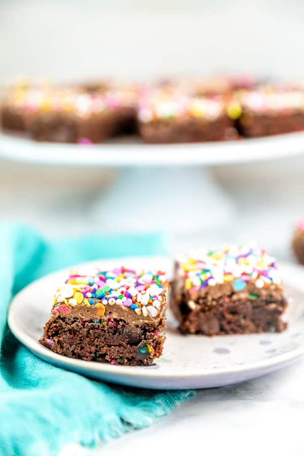 two thick brownies covered in chocolate frosting and colorful sprinkles