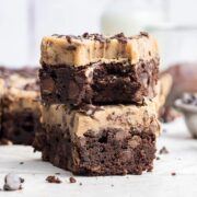 two brownies covered with chocolate chip cookie dough stacked vertically with a bite taken out of one