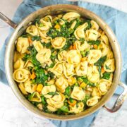 large skillet filled with saucy tortelllini, sweet potatoes, and spinach