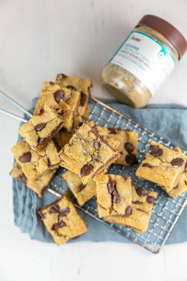 a pile of salted chocolate chip tahini blondies next to a jar of soom tahini