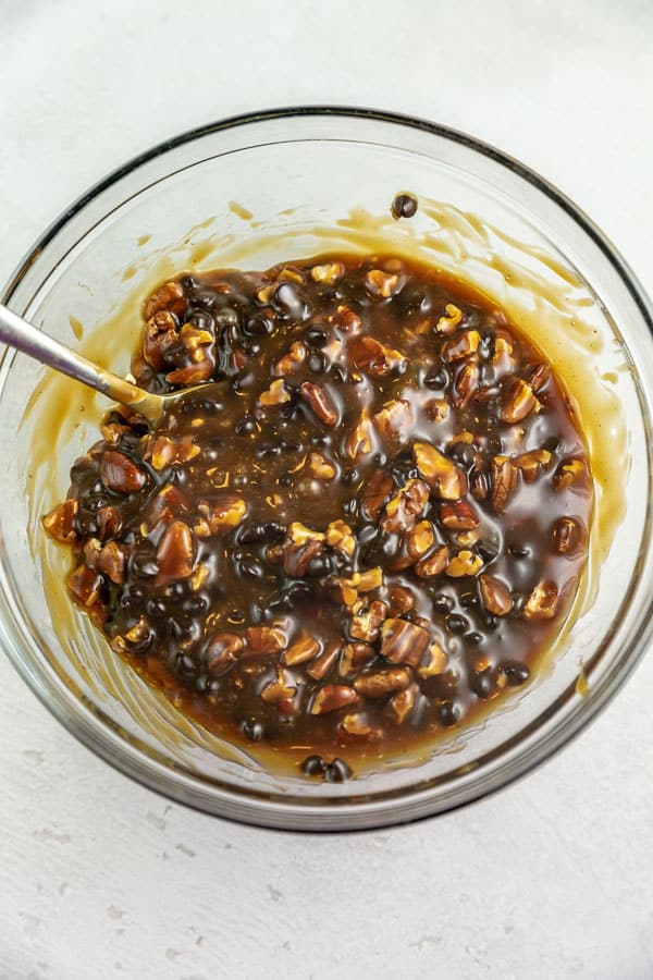 mixing bowl filled with salted caramel sauce, chocolate chips, and pecans