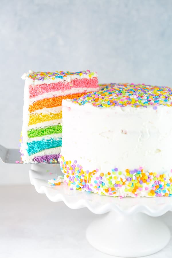 a slice of six layer rainbow cake being lifted with a cake server