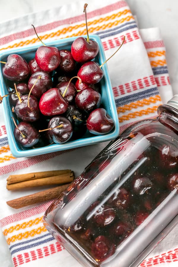 a pint of fresh cherries and a mason jar filled with cherries and whiskey