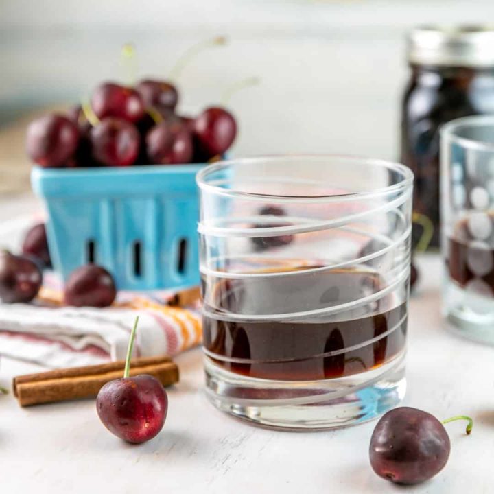 glass of cherry bounce with fresh cherries in the background