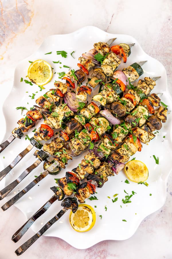 grilled kabobs with chicken and vegetables on a white serving plate