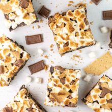 square brownies surrounded by chocolate, marshmallows, and graham crackers