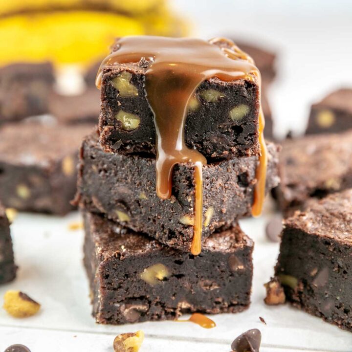 stack of 3 banana brownies filled with nuts and drizzled with salted caramel