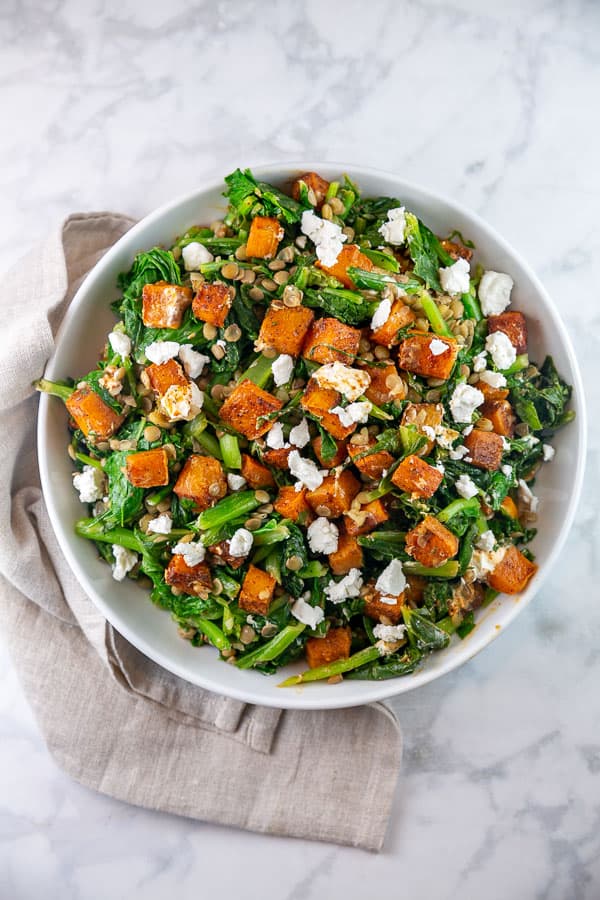 large white bowl filled with butternut squash, turnip greens, and lentil salad