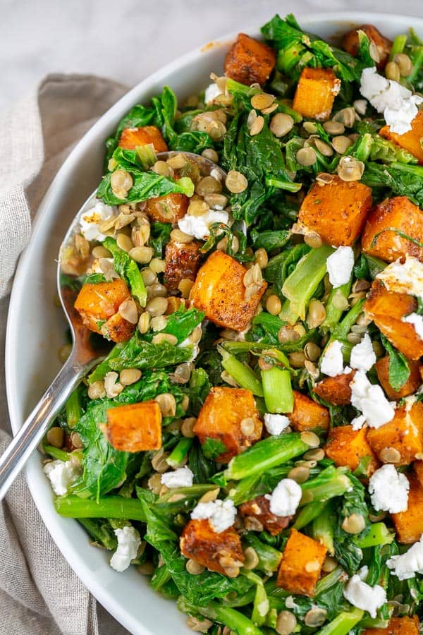 spicy butternut squash salad in a large bowl with a silver serving spoon.