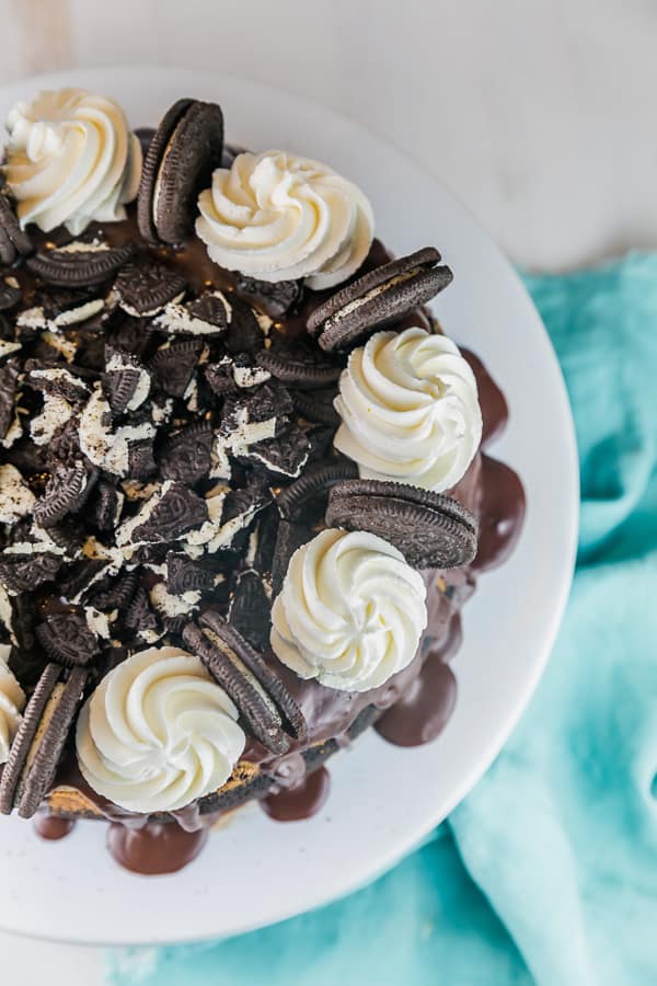 overhead view of an oreo cheesecake decorated with piped whipped cream and crushed oreos