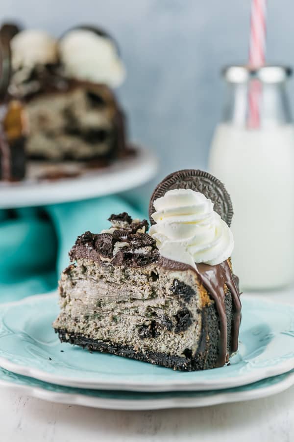 a large slice of cheesecake filled with oreos on a stack of dessert plates