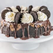 oreo cheesecake covered with chopped oreos on a cake stand
