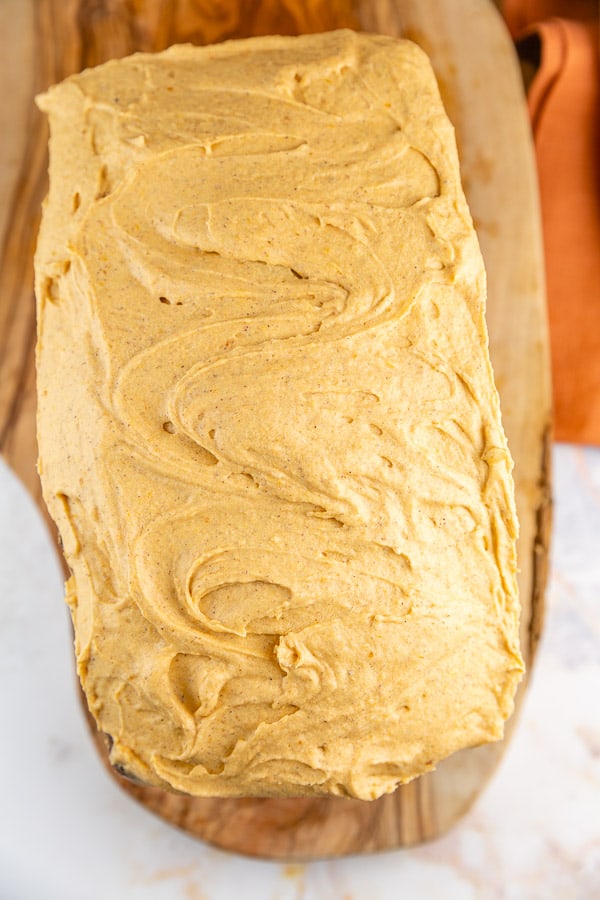 swirls of pumpkin buttercream frosting on a loaf of pumpkin bread.