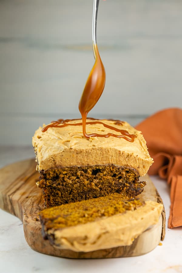 homemade salted caramel sauce on a spoon drizzling onto pumpkin bread.