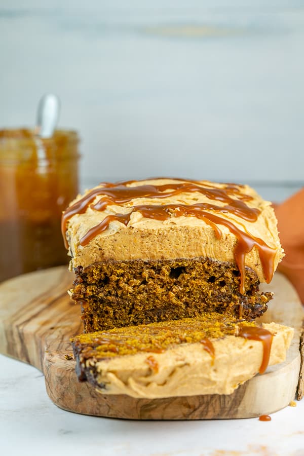 pumpkin bread with pumpkin frosting and salted caramel dripping down the side.