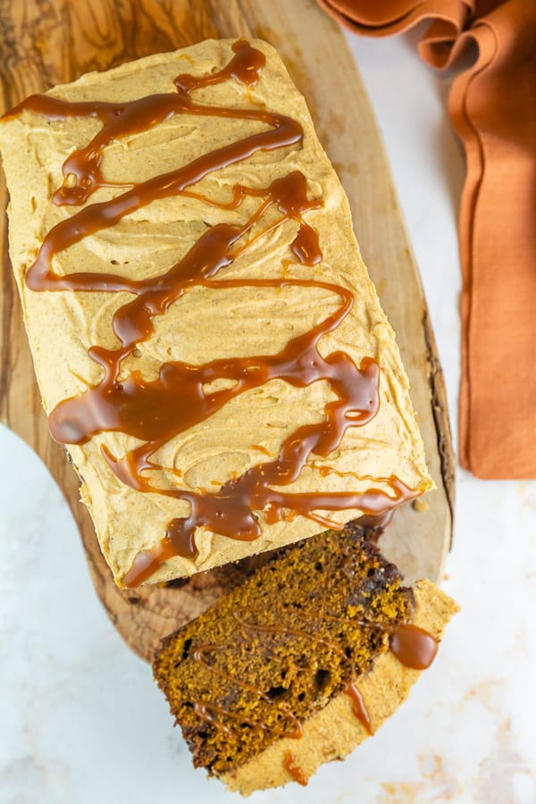 overhead view of pumpkin bread with caramel drizzle on a wooden board.