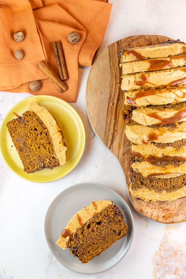 two slices of pumpkin bread with a thick layer of pumpkin frosting on small plates.