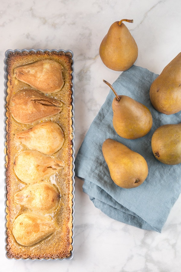 baked pear tart surrounded by fresh pears.