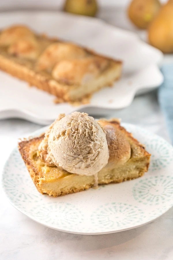 rectangular slice of pear tart with a scoop of homemade ice cream on top.