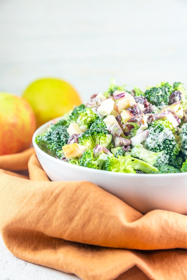 side view of fall broccoli salad piled high in a white serving bowl