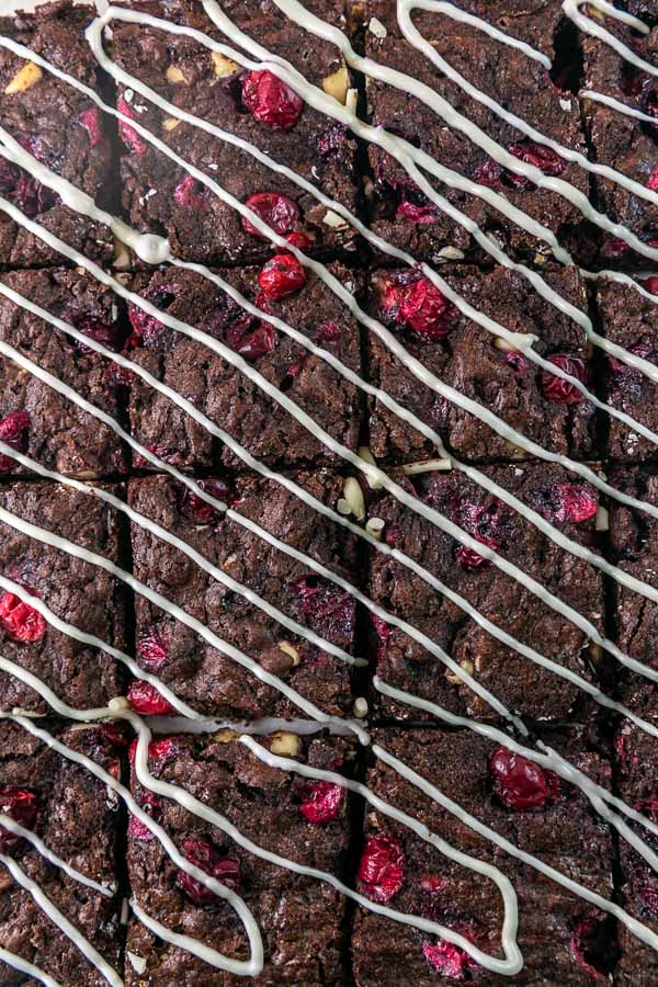 closeup of brownies with cranberries covered in a white chocolate drizzle.