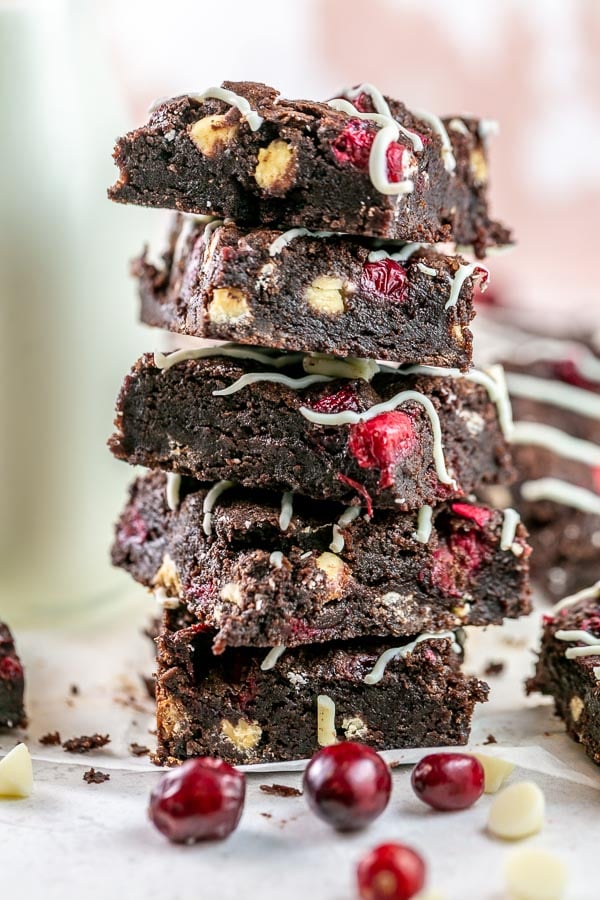 five brownies stacked in a pile surrounded by cranberries and white chocolate chips