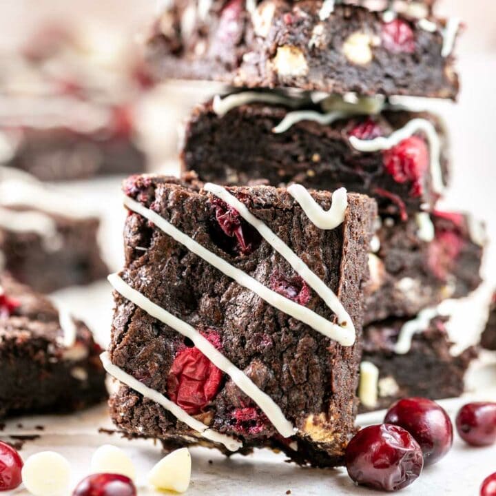 stack of brownies with cranberries and white chocolate chips covered with white chocolate drizzle