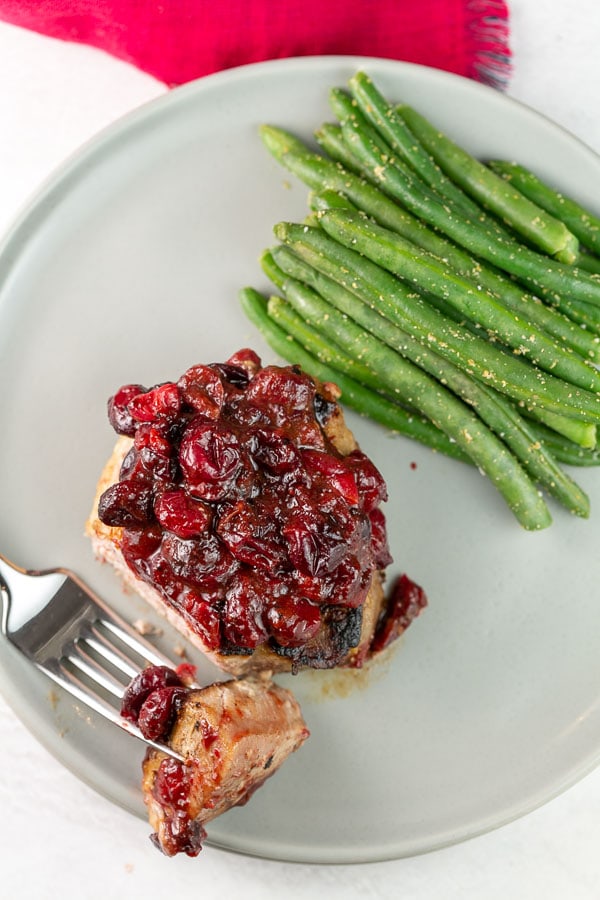 pork chop on a plate with steamed green beans.