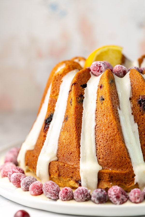 tall cranberry orange bundt cake with long drips of orange glaze.