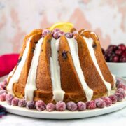 cranberry orange bundt cake decorated with orange glaze and sugared cranberries