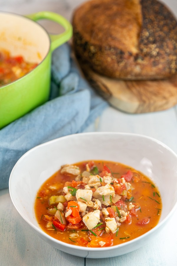 white soup bowl filled with tomato based fish stew