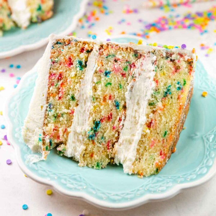 slice of three layer funfetti cake covered in sprinkles