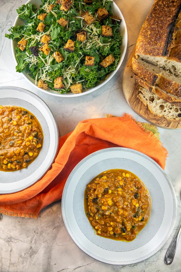 overhead view of two bowls of soup with a kale salad.