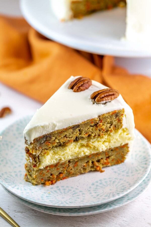 slice of cake with two slices of carrot cake and a layer of cheesecake in the middle