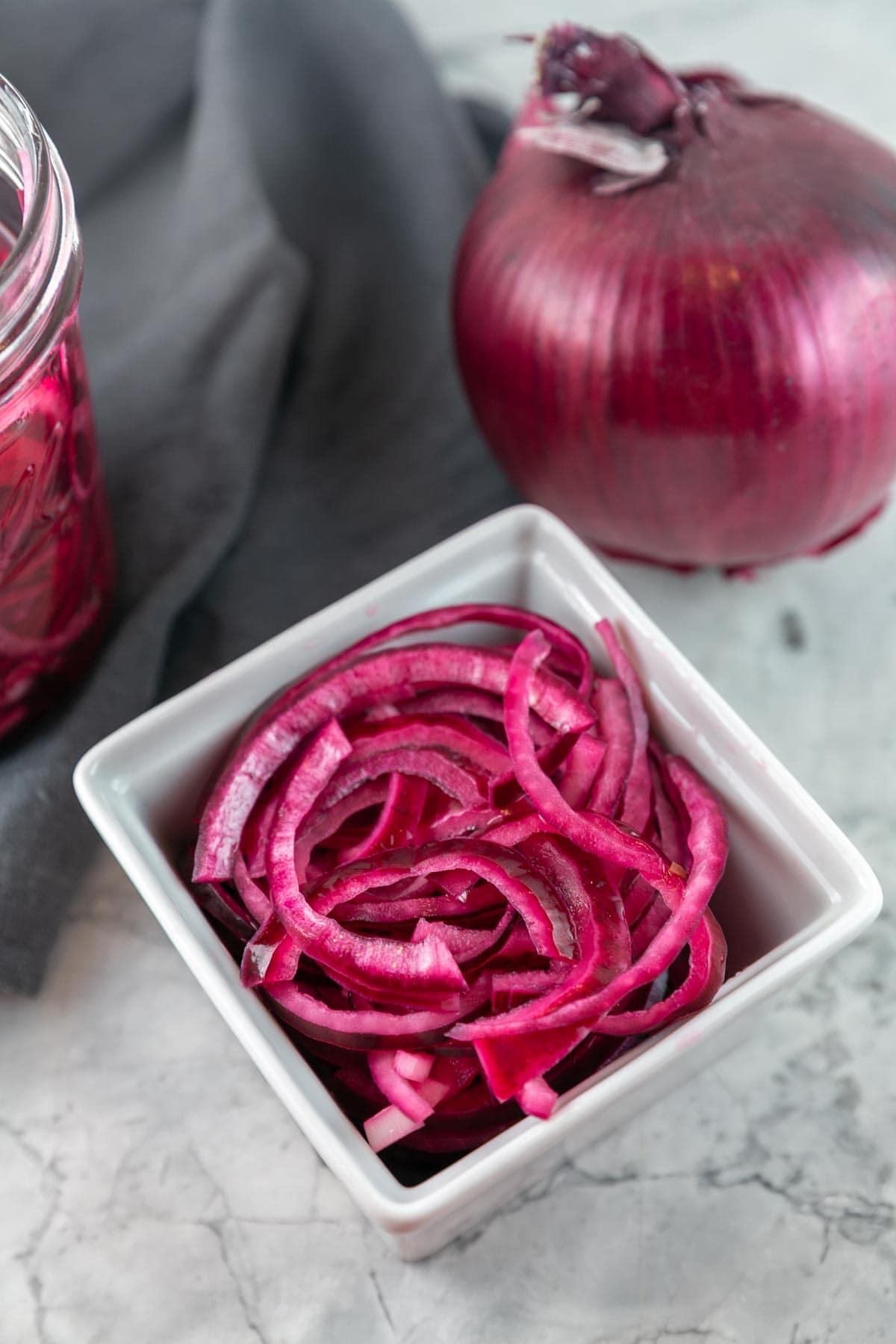 quick pickled red onions in a small white square bowl