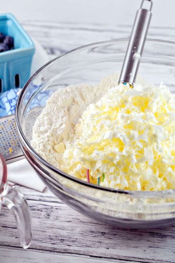 a pile of frozen butter grated into a mixing bowl filled with dry ingredients