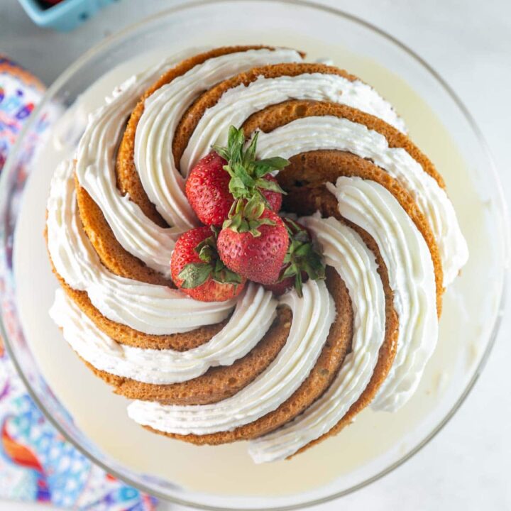 tres leches bundt cake covered with spirals of whipped cream