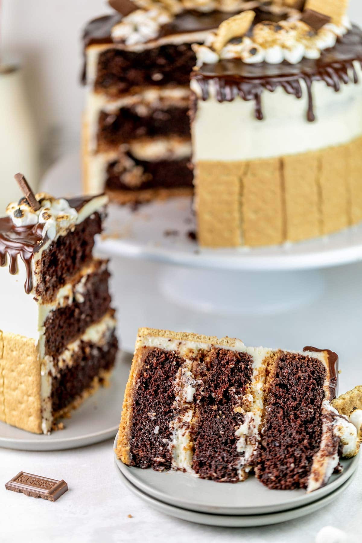 slice of three layer chocolate cake with a graham cracker crust and marshmallow buttercream