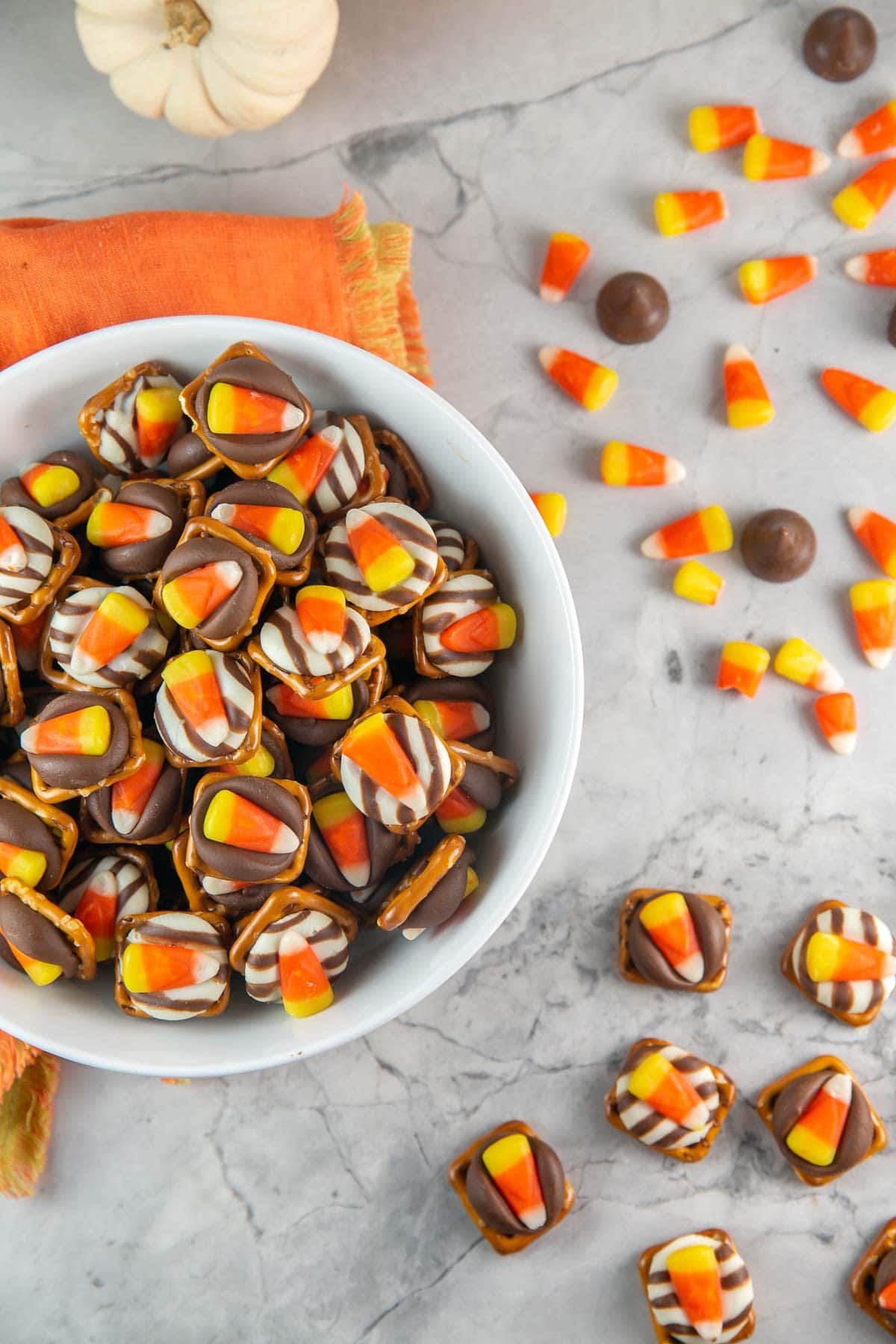 bowl of candy corn pretzel bites with candy corn and kisses scattered in the background.
