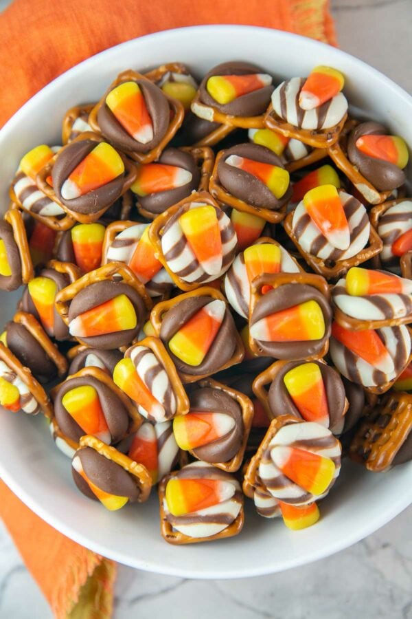 large bowl filled with pretzels covered with a kiss and a piece of candy corn